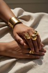 South Asian skin – chunky gold rings & cuff bracelet, hands close-up
